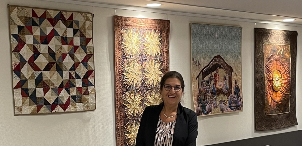 Elly Prins bij haar quilts in de Herberg-zaal